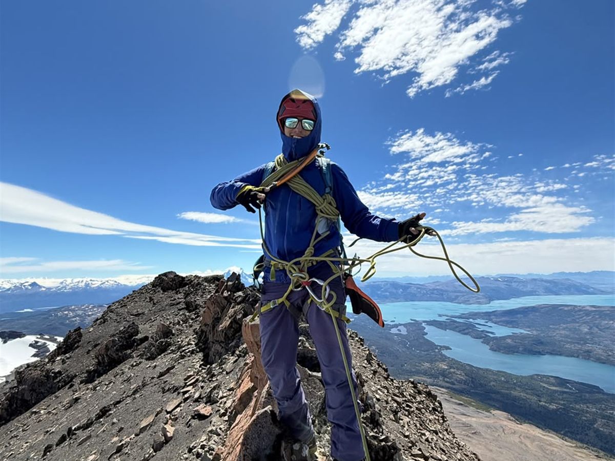 Montañista en el filo de cumbre recogiendo la cuerda sobre el lago, Patagonia